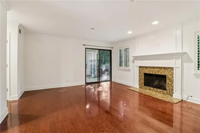 a view of an empty room with wooden floor fireplace and a window