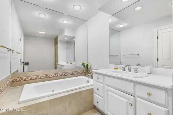a spacious bathroom with a tub sink and mirror