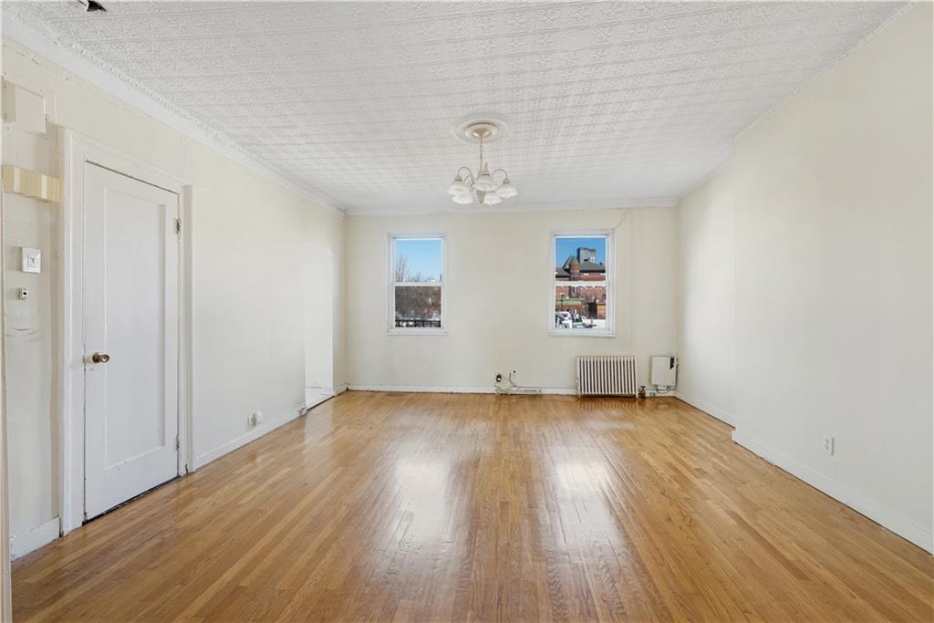 151 Kane Street Brooklyn, NY 11201 - Photo 8 of 14 an empty room with wooden floor chandelier fan and windows