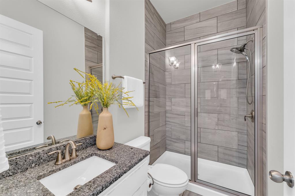 110 Magona Trail Georgetown, TX 78628 - Photo 18 of 38 A well-appointed bathroom features a granite-topped vanity and a tiled shower enclosure.