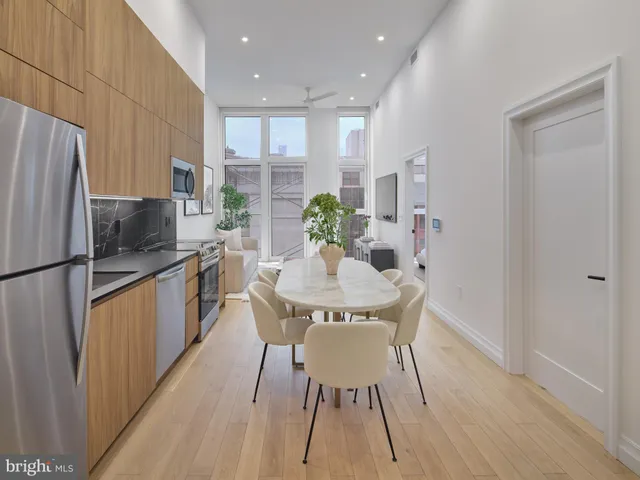 a kitchen with stainless steel appliances granite countertop a refrigerator a sink a stove a dining table and chairs