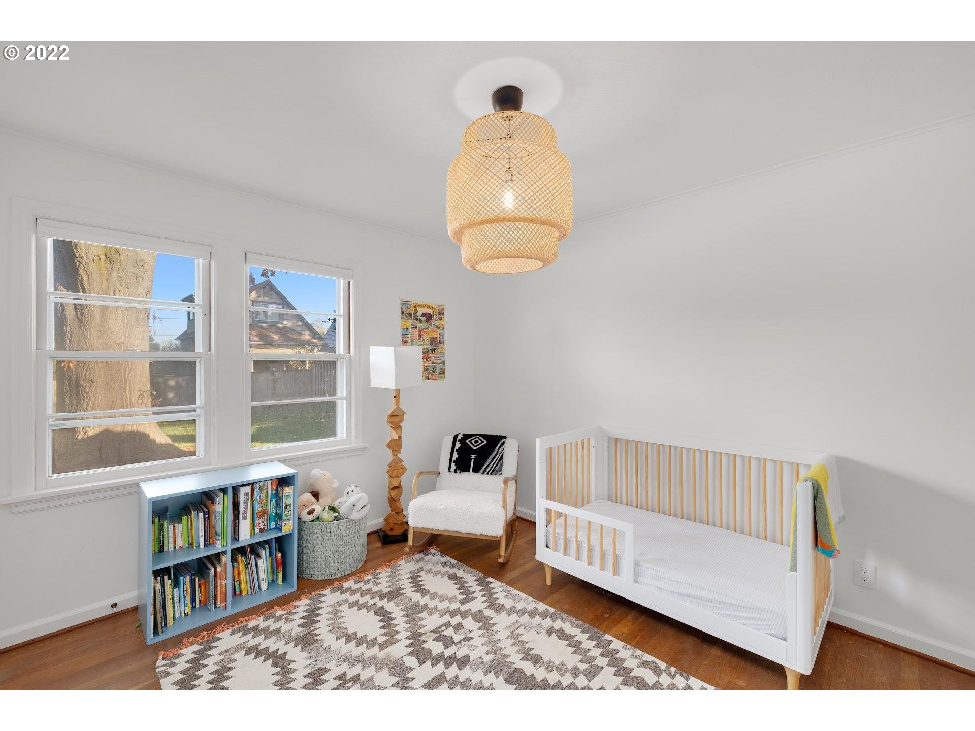5555 Southeast Stark Street Portland, OR 97215 - Photo 16 of 21 a living room with a baby crib furniture a chandelier and a book shelf