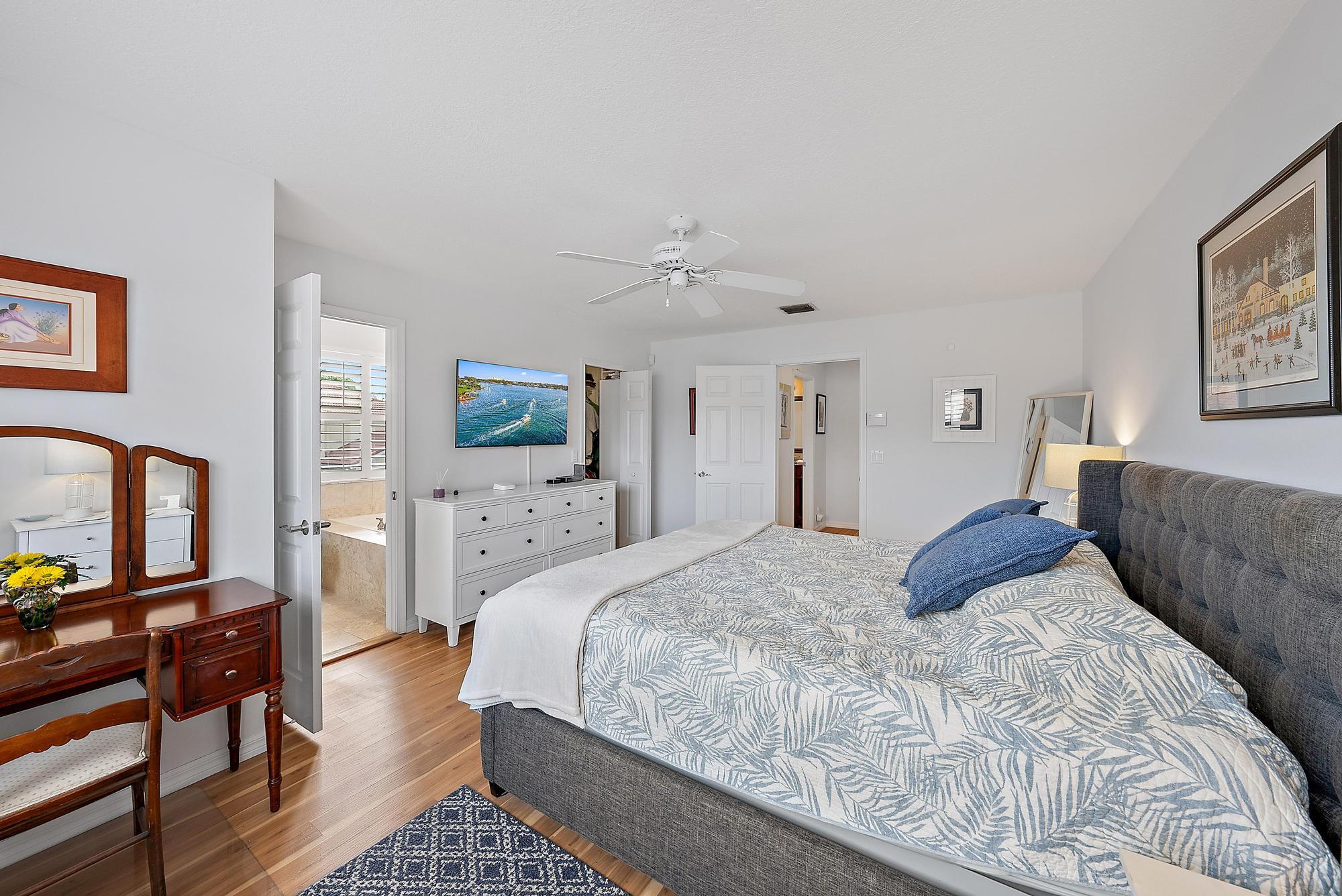 149 Stonebriar Boulevard Jupiter, FL 33458 - Photo 15 of 42 a spacious bedroom with a bed a couch and a flat tv screen on dresser