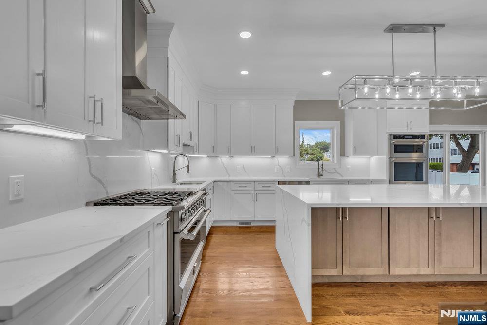 55 Maiden Lane Bergenfield, NJ 07621 - Photo 18 of 49 a kitchen with kitchen island granite countertop a sink stove and cabinets