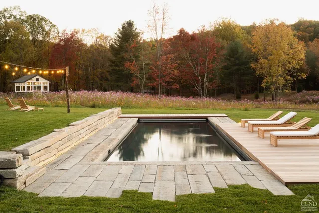 a view of swimming pool on a sunny day with lawn chairs