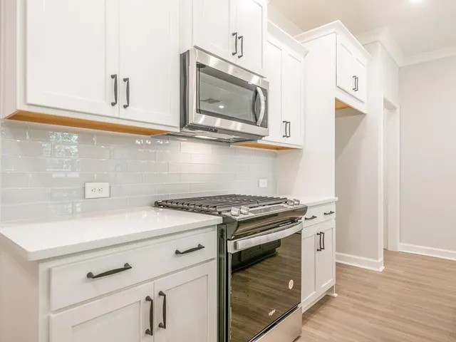 a kitchen with stainless steel appliances white cabinets and a stove top oven