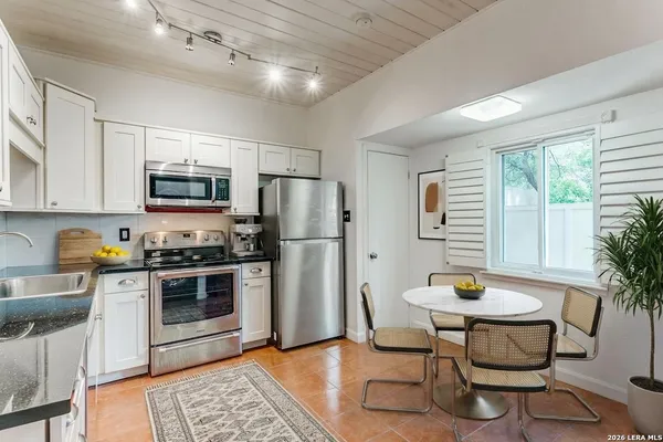 a kitchen with stainless steel appliances a dining table chairs stove refrigerator and microwave