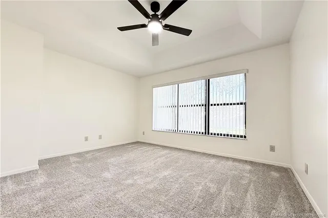 an empty room with a ceiling fan and windows