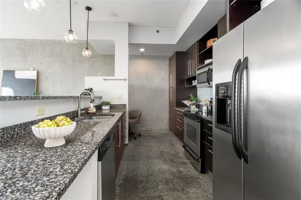a kitchen with stainless steel appliances granite countertop a refrigerator a oven a sink a dining table and chairs with wooden floor