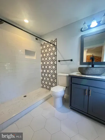 a bathroom with a granite countertop sink a toilet and shower