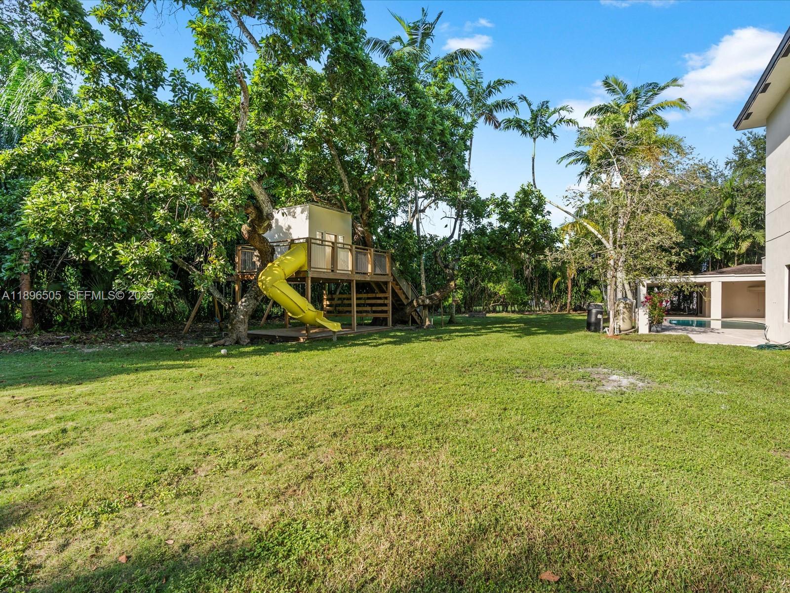 8501 Southwest 68th St Road Miami, FL 33143 - Photo 41 of 51 One-acre fenced yard with treehouse, jungle gym, covered outdoor kitchen, and deck — perfect for kids, pets, and entertaining, with space to add a tennis or pickleball court.
