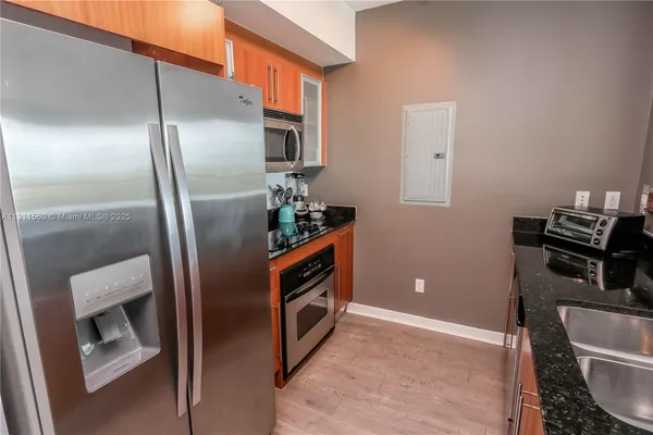 a kitchen with stainless steel appliances granite countertop a refrigerator a stove and a sink