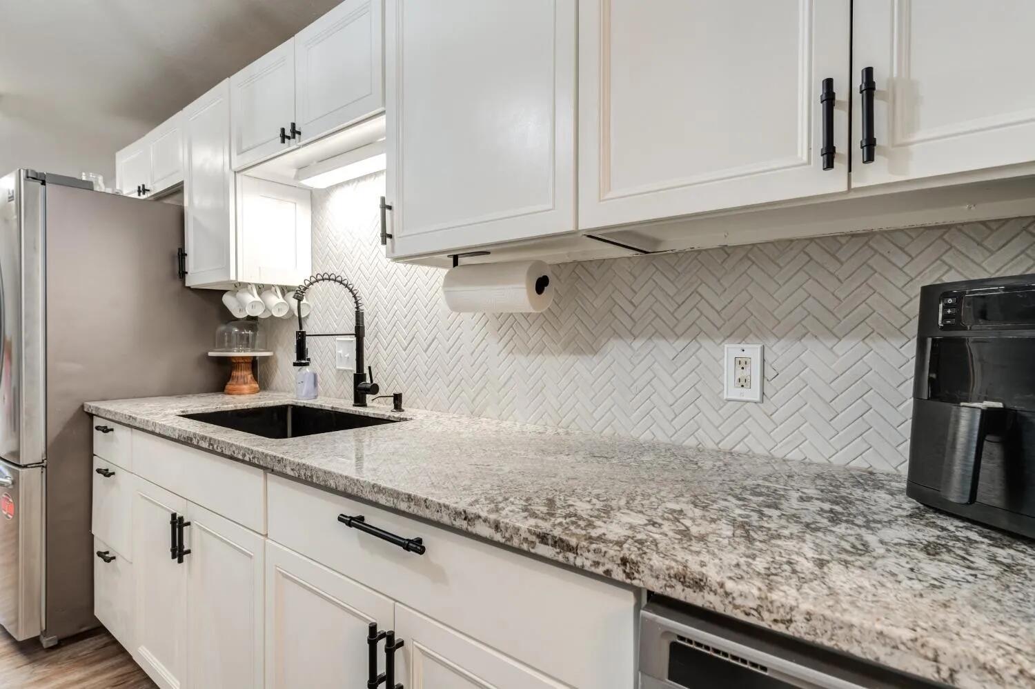 2407 46th Street Lubbock, TX 79412 - Photo 2 of 10 a kitchen with granite countertop a sink stainless steel appliances and cabinets