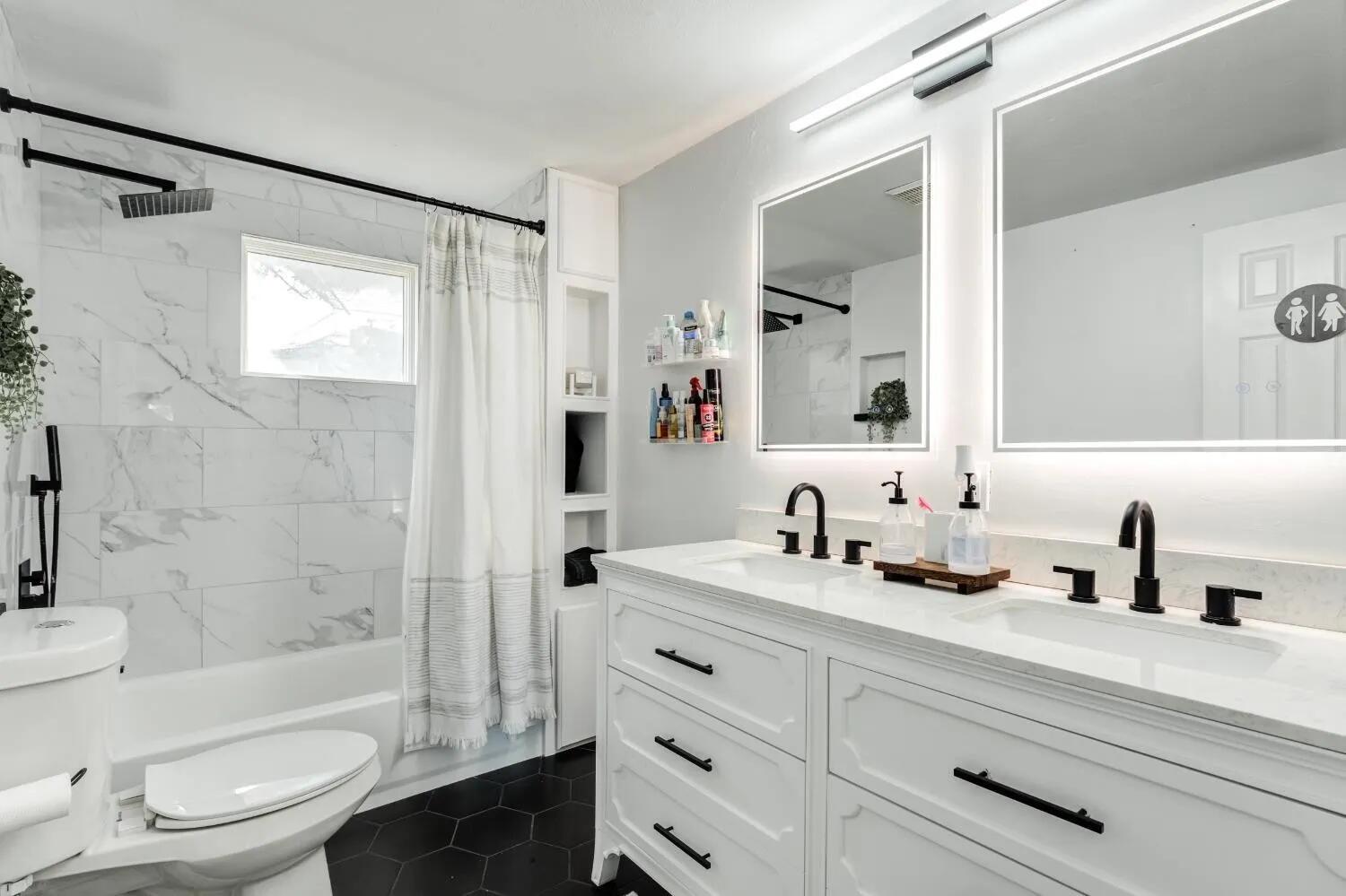 2407 46th Street Lubbock, TX 79412 - Photo 6 of 10 a bathroom with a sink a toilet a mirror a vanity a bathtub and shower