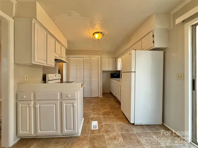 a kitchen with stainless steel appliances granite countertop a refrigerator a stove and white cabinets