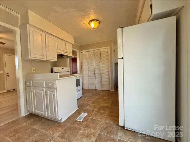 a kitchen with white cabinets and refrigerator