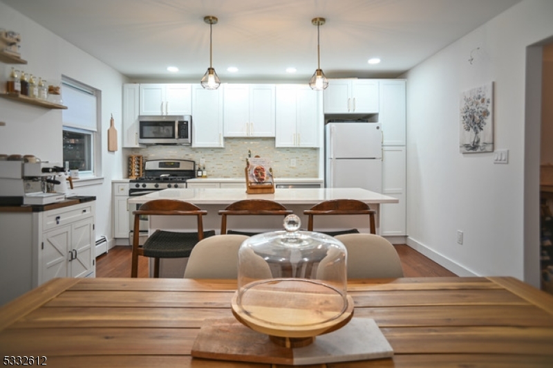 a kitchen with stainless steel appliances kitchen island granite countertop a sink a stove a refrigerator and cabinets