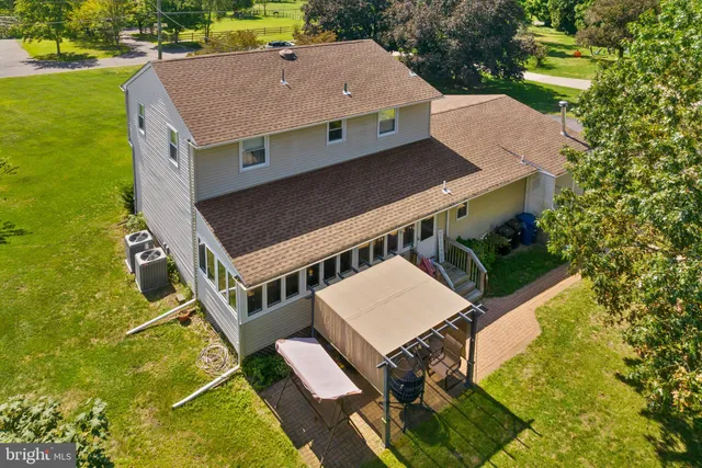 an aerial view of a residential houses with outdoor space and trees all around