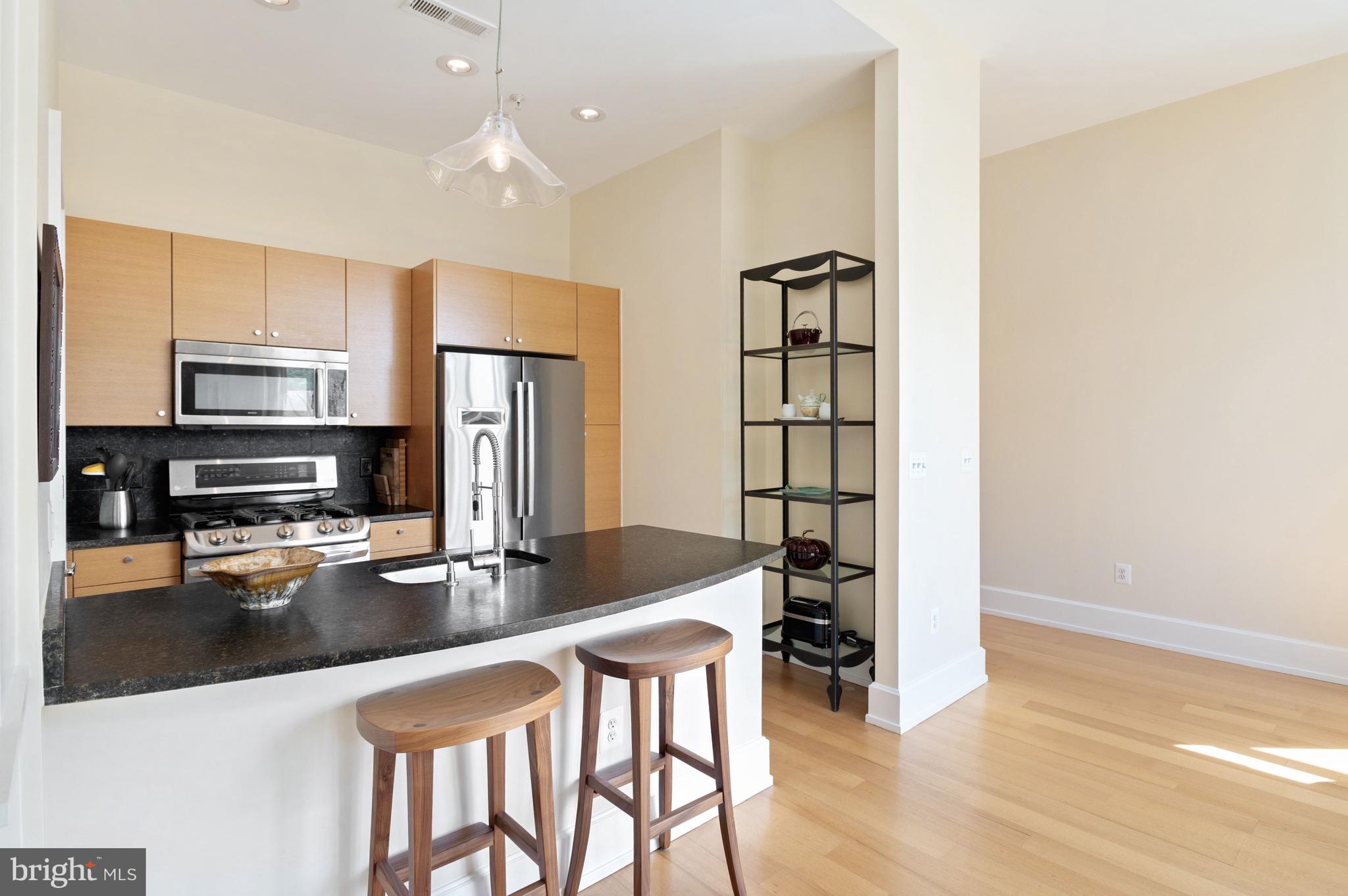 2516 Q Street Northwest, Unit C201 Washington, DC 20007 - Photo 5 of 20 a kitchen with stainless steel appliances granite countertop a refrigerator a stove top oven a sink dishwasher and white cabinets with wooden floor