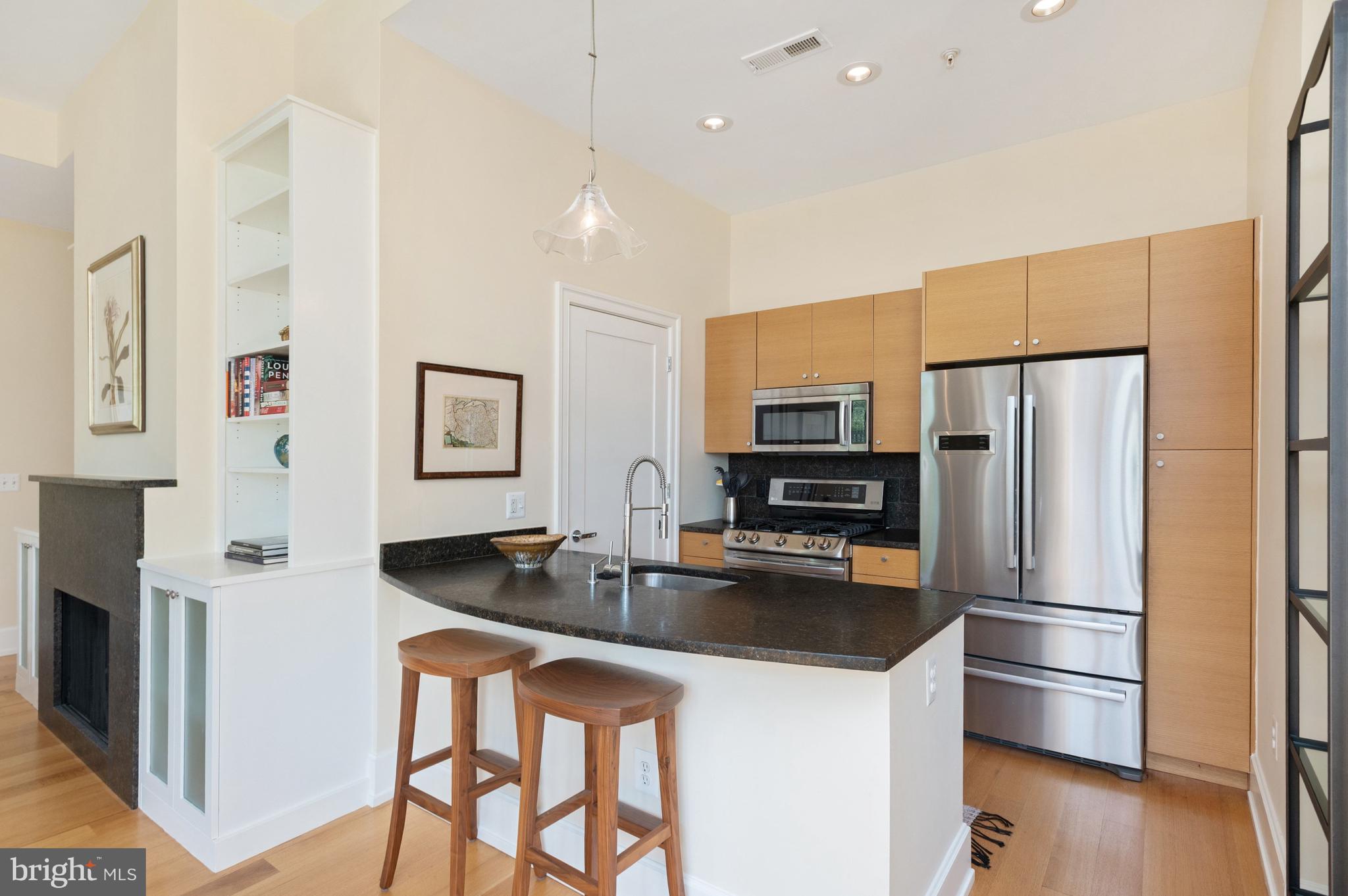 2516 Q Street Northwest, Unit C201 Washington, DC 20007 - Photo 7 of 20 a kitchen with stainless steel appliances granite countertop a refrigerator a stove a sink a microwave oven with a dining table and chairs
