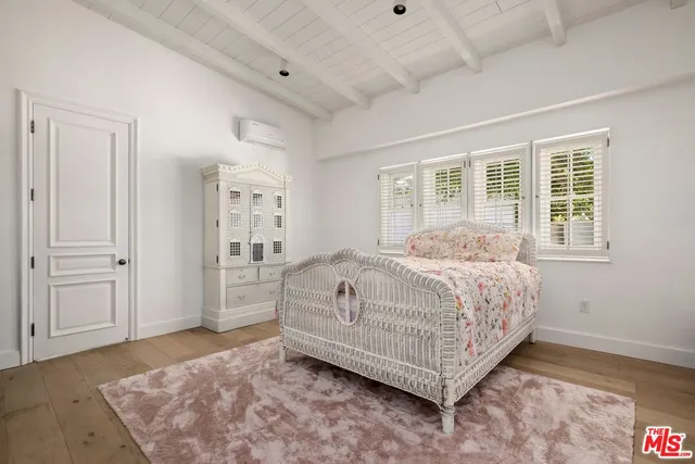 a bedroom with a bed rug and wooden floor