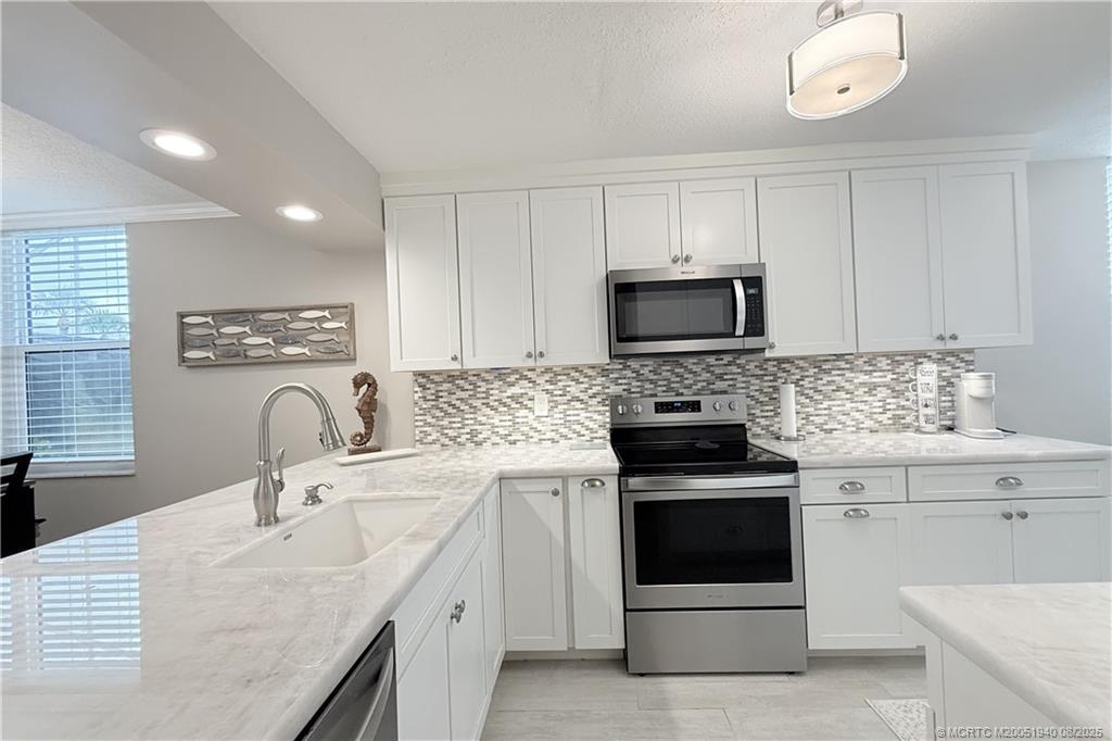 1950 Southwest Palm City Road, Unit 9108 Stuart, FL 34994 - Photo 4 of 37 a kitchen with sink a microwave a stove and cabinets