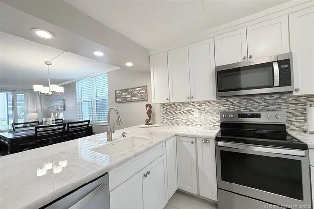 a kitchen with granite countertop white cabinets and stainless steel appliances