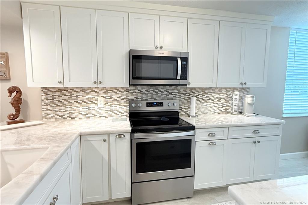 1950 Southwest Palm City Road, Unit 9108 Stuart, FL 34994 - Photo 6 of 37 a kitchen with granite countertop white cabinets and stainless steel appliances