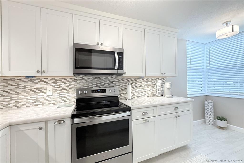 1950 Southwest Palm City Road, Unit 9108 Stuart, FL 34994 - Photo 9 of 37 a kitchen with granite countertop white cabinets and stainless steel appliances