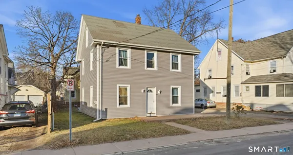a view of a white house with large windows next to road