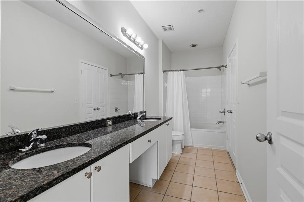 10 Perimeter Summit Boulevard, Unit 3311 Atlanta, GA 30319 - Photo 61 of 68 a bathroom with a granite countertop sink a mirror and a shower
