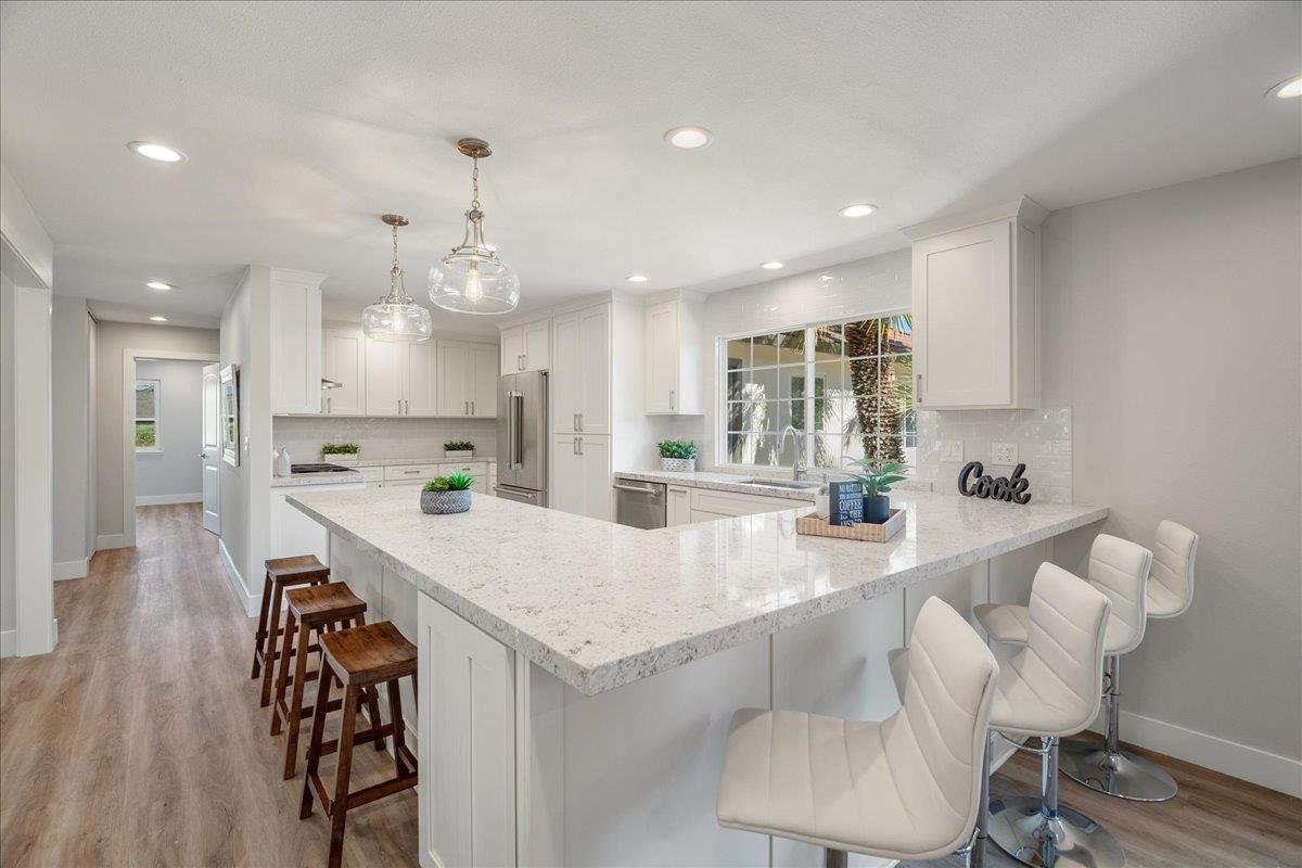 7106 Brooktree Way San Jose, CA 95120 - Photo 14 of 31 a large kitchen with kitchen island a stove a sink a refrigerator and a dining table with wooden floor