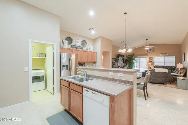 a kitchen with a sink a counter top space and living room view