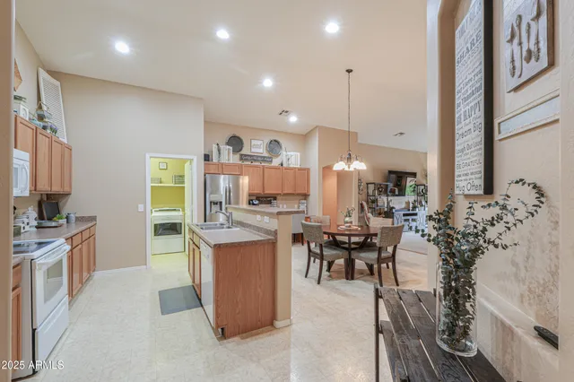 a kitchen with stainless steel appliances kitchen island granite countertop a table chairs and a refrigerator