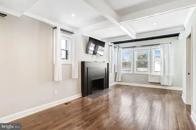a view of an empty room with window and wooden floor