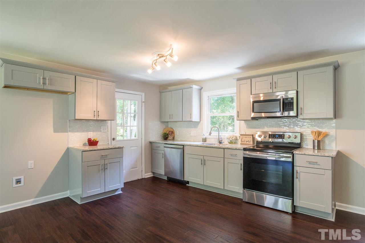 a kitchen with stainless steel appliances white cabinets a sink and dishwasher a stove with wooden floor