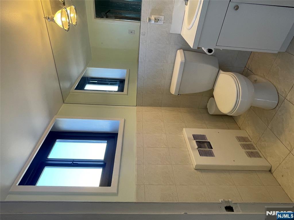 90 Prospect Avenue, Unit 8E Hackensack, NJ 07601 - Photo 14 of 21 a bathroom with a toilet a sink and a mirror