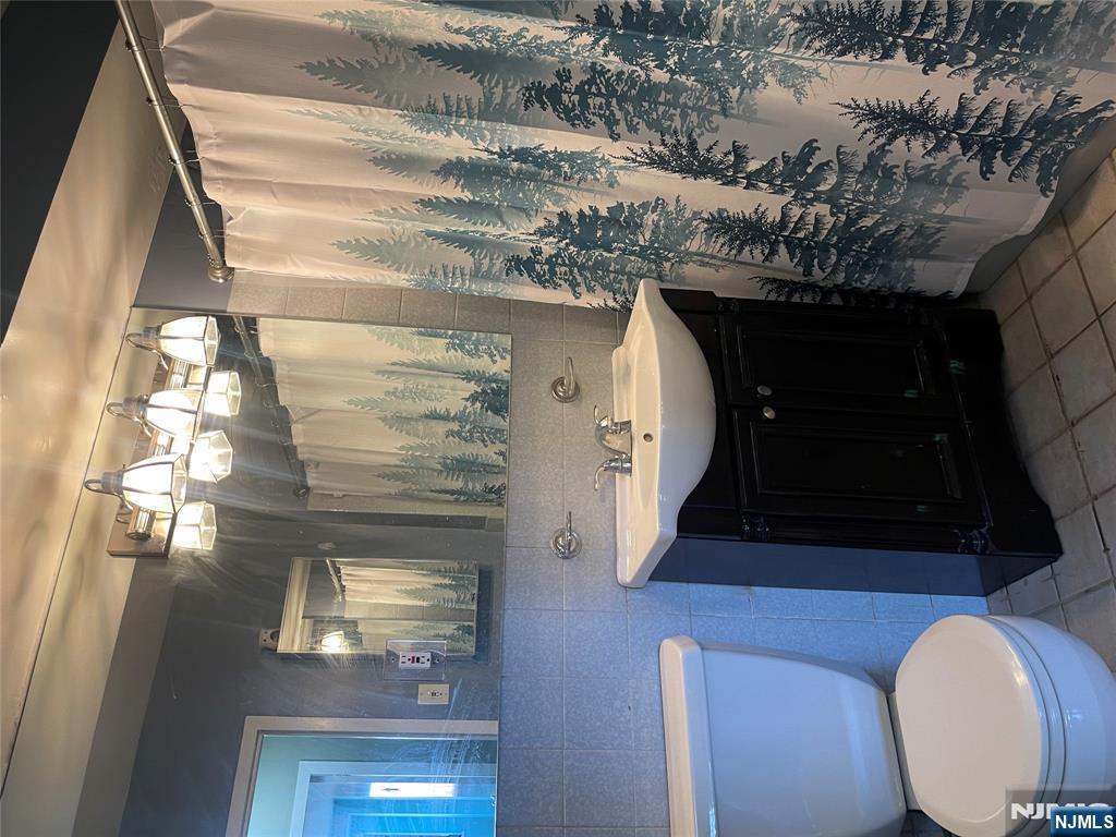 90 Prospect Avenue, Unit 8E Hackensack, NJ 07601 - Photo 15 of 21 a bathroom with a sink a toilet a mirror and shower curtain