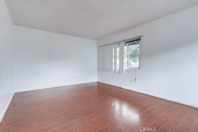 a view of an empty room with wooden floor and window