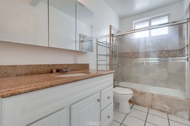 a bathroom with a granite countertop sink a toilet and a shower