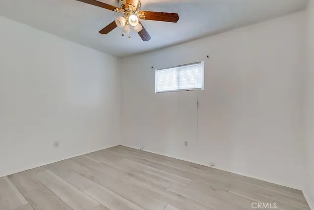 an empty room with a window and a ceiling fan