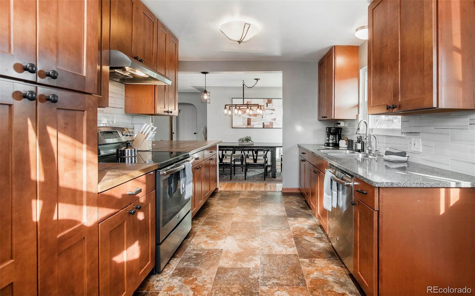 6480 Garrison Street Arvada, CO 80004 - Photo 11 of 40 a kitchen with stainless steel appliances granite countertop a stove a sink and a refrigerator