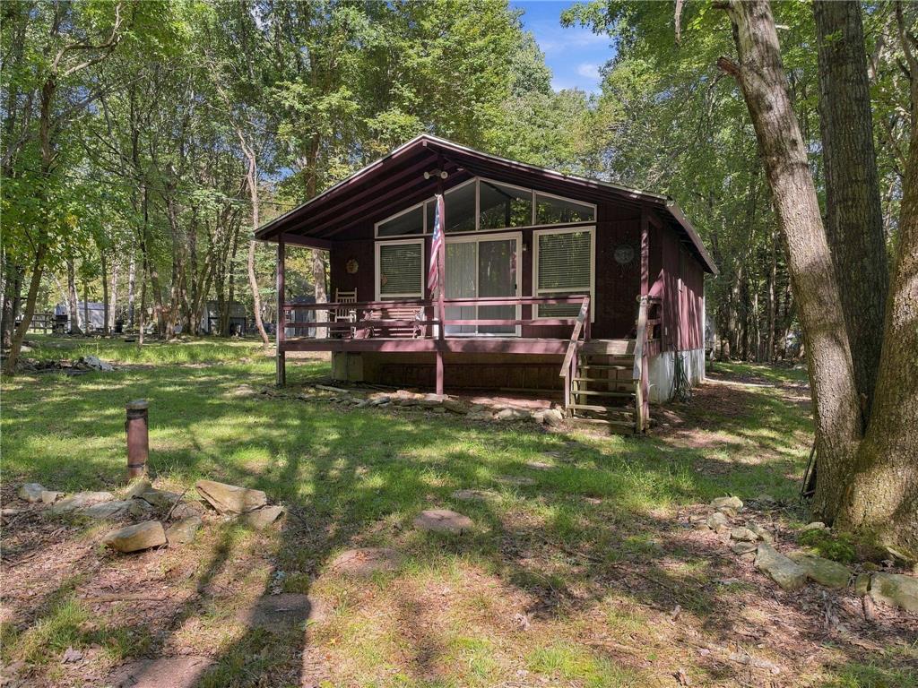 116 Aspen Road Albrightsville, PA 18210 - Photo 3 of 33 A raised wooden deck overlooks a grassy clearing shaded by mature trees.