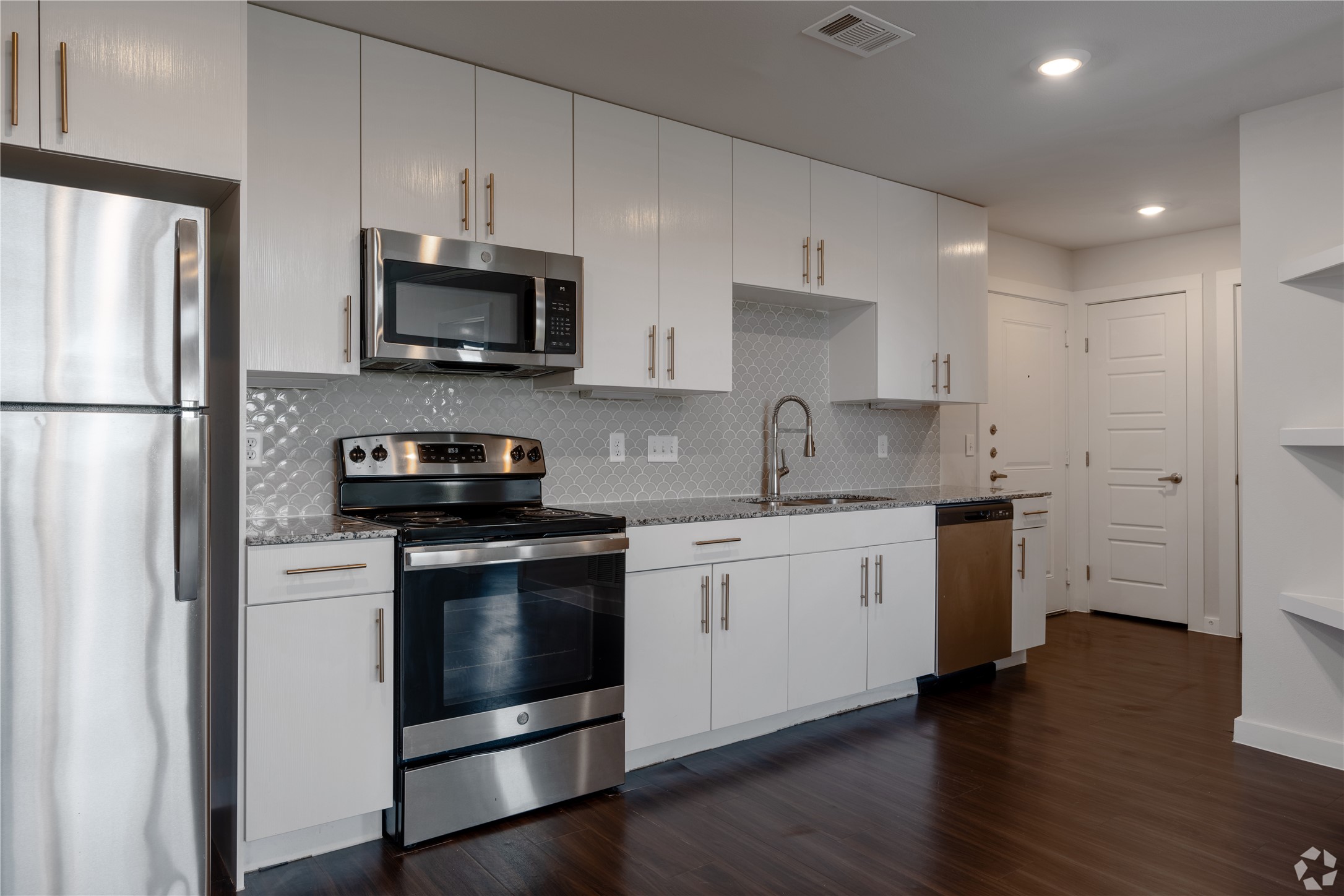 2401 East Oltorf Street, Unit 170 Austin, TX 78741 - Photo 11 of 14 a kitchen with stainless steel appliances granite countertop a refrigerator stove a sink and a microwave