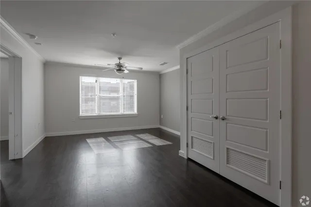 an empty room with wooden floor cabinet and windows