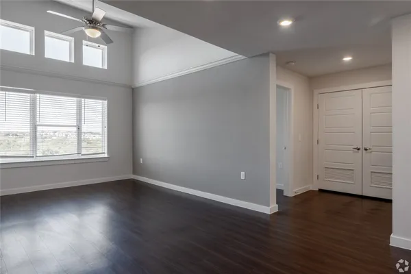 an empty room with wooden floor and windows with curtains