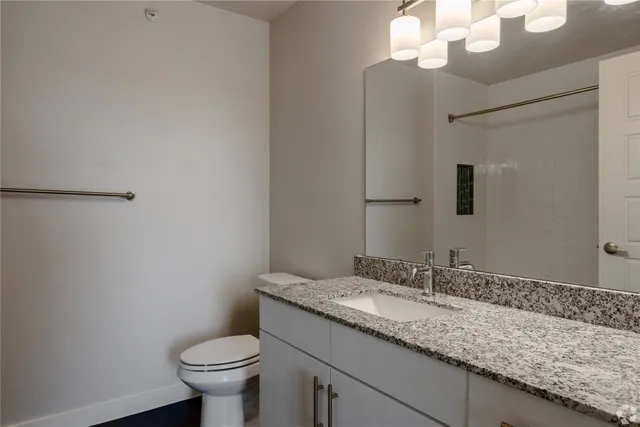 a bathroom with a granite countertop sink a toilet and a mirror