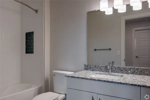 a bathroom with a granite countertop sink a toilet and bathtub