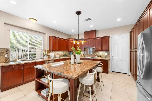 a kitchen with stainless steel appliances granite countertop a kitchen island a stove and a refrigerator