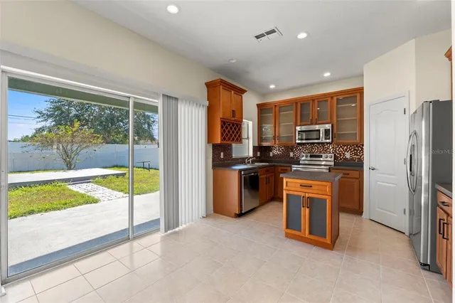 a kitchen with stainless steel appliances granite countertop a refrigerator a sink a stove top oven and a refrigerator